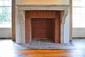Rustic stone fireplace featuring a fireback made from reclaimed clay roof tiles installed vertically along the sides and top