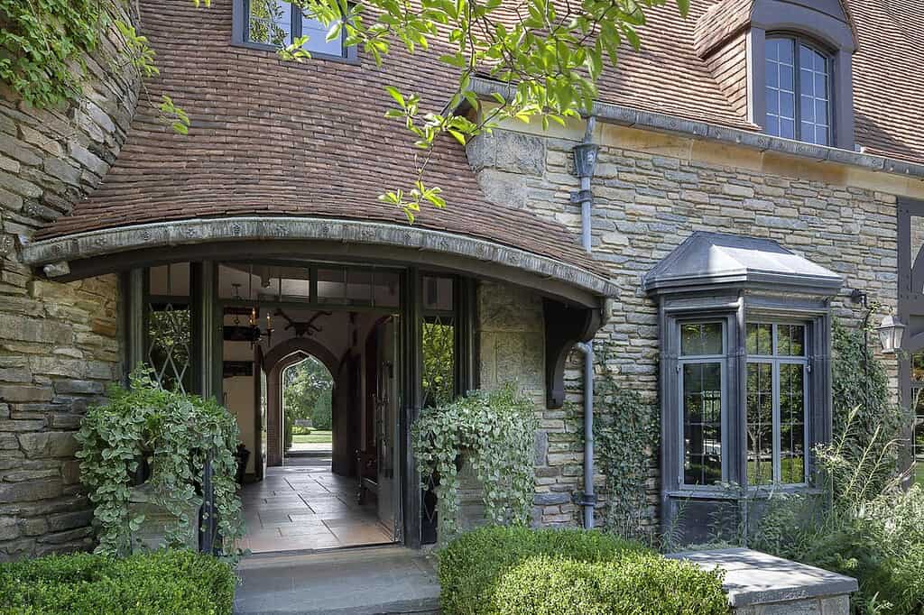 Stone home with steep pitched roof and curved clay roof tiles, showing historic architecture and heritage roofing craftsmanship.