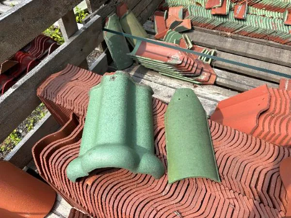 Ludowici Dull Green 206 ridge tile and 102 hip tile displayed on pallets of reclaimed clay roof tiles.